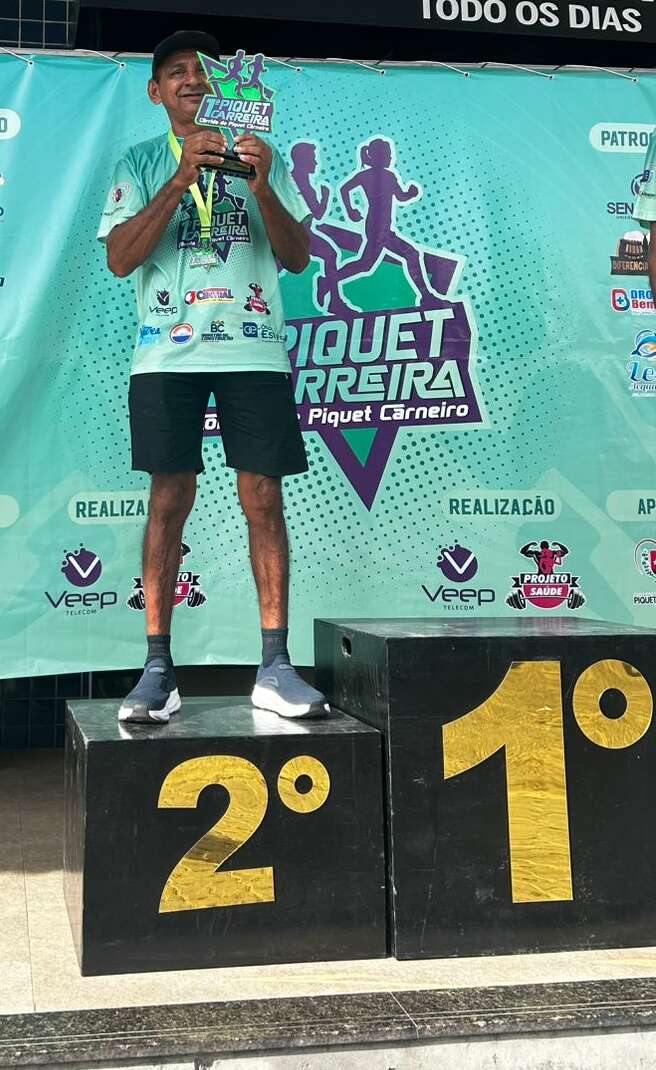 Foto de Juaci Barros no segundo lugar do pódio, segurando um troféu, depois de correr a 1ª Piquet Carreira