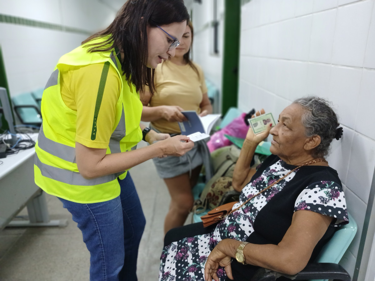 Enfermeira com colete de segurança "fiscaliza" cartão de vacinas de paciente atendida no CIDH